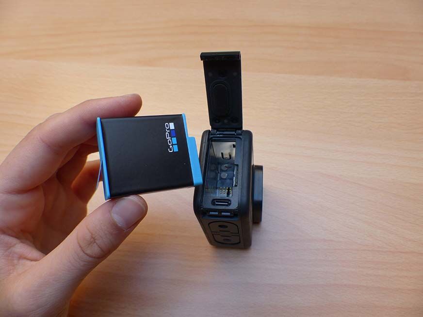 Man sieht, wie der Akku aus der GoPro Hero 9 herausgenommen wird. 